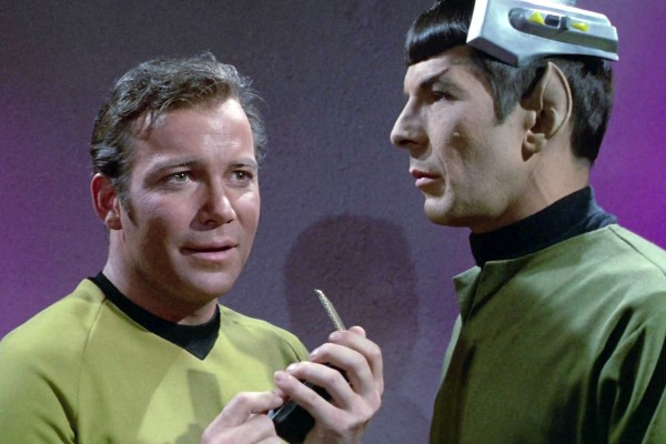 William Shatner as Captain James T. Kirk speaks into his communicator with Leonard Nimoy as Mr. Spock in the STAR TREK 